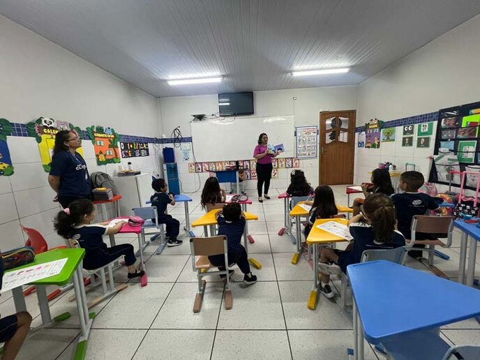 Helení apresentando o personagem Pedro para os alunos e professora em sala.