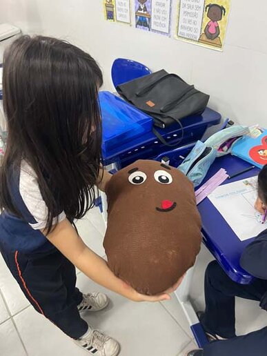 Criança segurando o boneco da fruta Cupuaçu